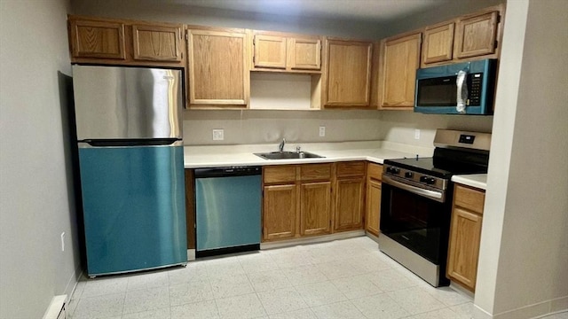 kitchen featuring baseboards, light floors, light countertops, a sink, and stainless steel appliances
