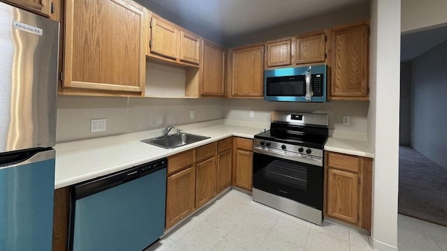 kitchen featuring brown cabinetry, a sink, appliances with stainless steel finishes, and light countertops