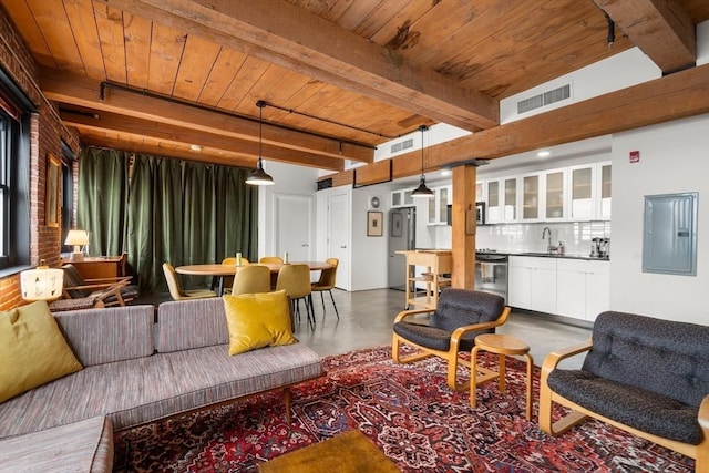 living room featuring concrete flooring, sink, wood ceiling, electric panel, and beam ceiling