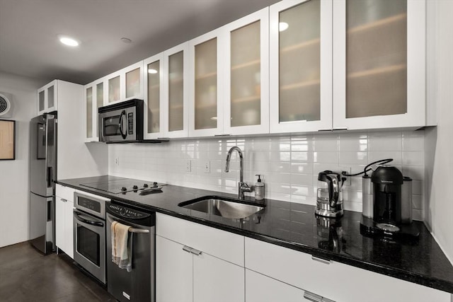 kitchen featuring sink, dark stone countertops, white cabinets, decorative backsplash, and stainless steel appliances