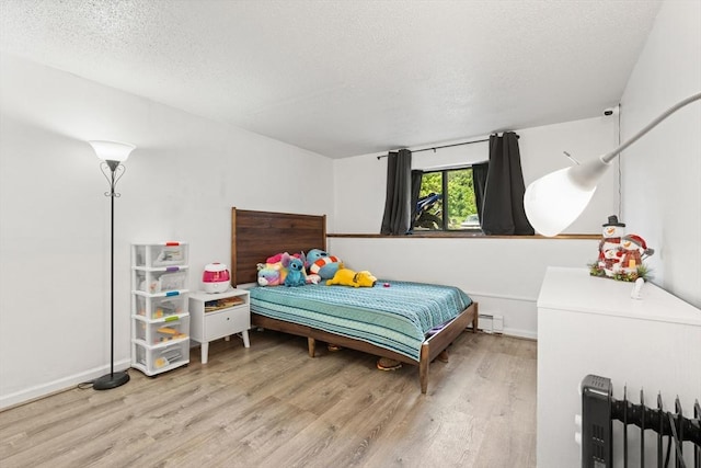 271 Humphrey St Unit H2, Lowell, MA 01850 - bedroom with wood finished floors, a textured ceiling, a baseboard heating unit, and radiator