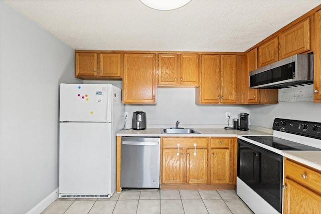 271 Humphrey St Unit H2, Lowell, MA 01850 - kitchen featuring appliances with stainless steel finishes, light countertops, light tile patterned floors, and brown cabinetry