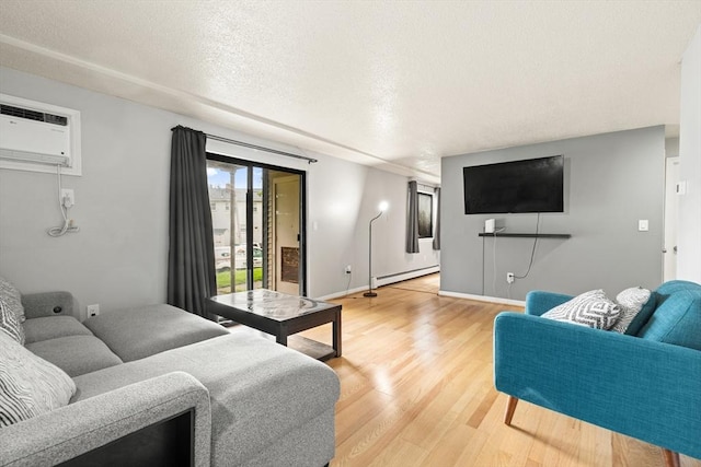 271 Humphrey St Unit H2, Lowell, MA 01850 - living area with baseboard heating, light wood finished floors, a wall mounted air conditioner, and a textured ceiling