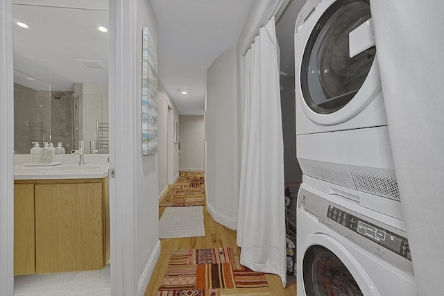 washroom featuring laundry area, stacked washer and dryer, visible vents, baseboards, and light wood-style floors