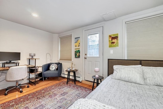 bedroom with a baseboard radiator, recessed lighting, and wood finished floors