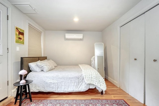 bedroom featuring an AC wall unit, wood finished floors, and a closet