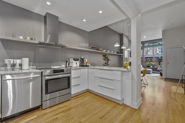 kitchen with open shelves, appliances with stainless steel finishes, light stone counters, light wood finished floors, and wall chimney exhaust hood
