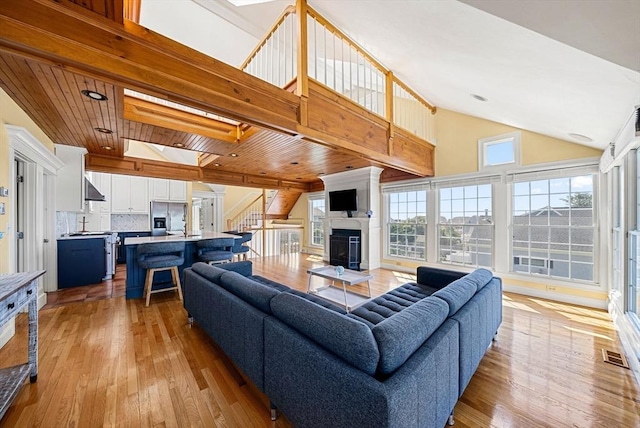 328 Central Ave, Scituate, MA 02050 - living room featuring light wood finished floors, stairway, a glass covered fireplace, high vaulted ceiling, and wooden ceiling