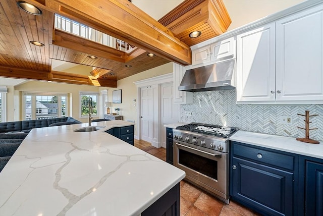 328 Central Ave, Scituate, MA 02050 - kitchen featuring stainless steel stove, wall chimney range hood, blue cabinetry, open floor plan, and tasteful backsplash