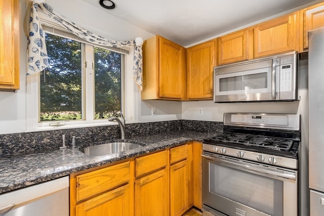 kitchen featuring sink, appliances with stainless steel finishes, and dark stone counters