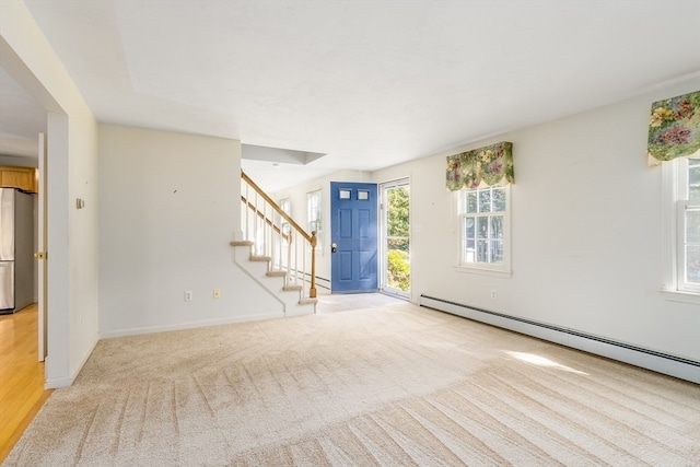 empty room featuring light hardwood / wood-style floors, a baseboard heating unit, and plenty of natural light