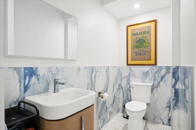 bathroom featuring tile patterned flooring, vanity, toilet, and tile walls