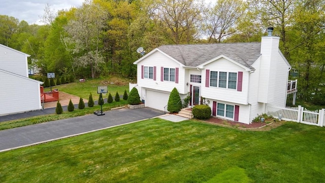 split foyer home with a garage, asphalt driveway, a chimney, and roof with shingles