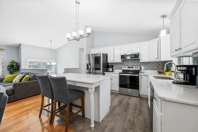 kitchen with stainless steel appliances, a chandelier, a sink, open floor plan, and tasteful backsplash