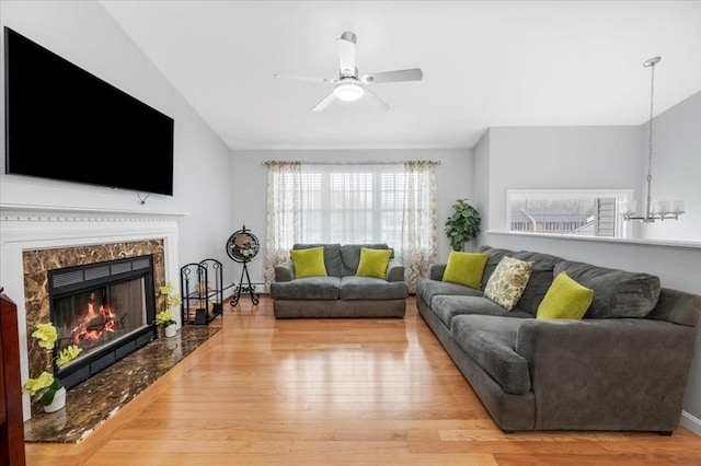 living area with a ceiling fan, wood finished floors, and a premium fireplace