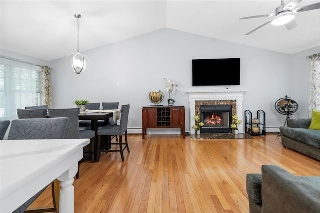 living room featuring lofted ceiling, light wood-style floors, a ceiling fan, and a premium fireplace