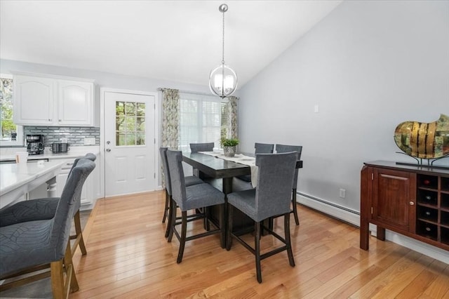 dining room with a baseboard radiator, vaulted ceiling, healthy amount of natural light, light wood-style flooring, and a chandelier