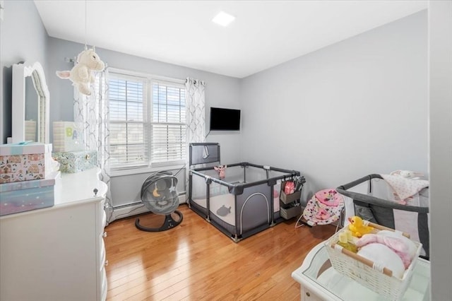 recreation room with light wood finished floors, a baseboard radiator, and baseboard heating