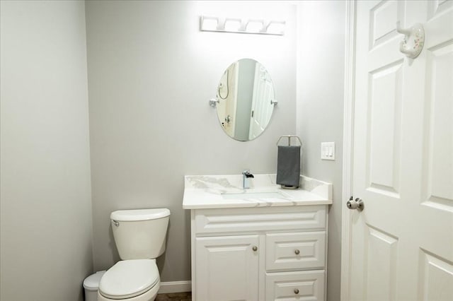 bathroom with toilet, vanity, and baseboards