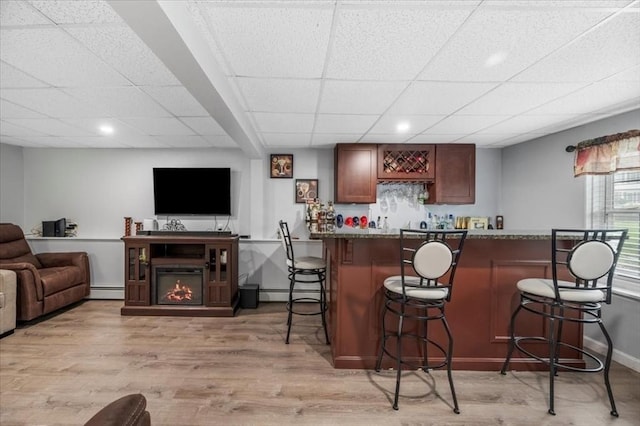 indoor bar with a baseboard heating unit, light wood-style flooring, a drop ceiling, recessed lighting, and baseboards
