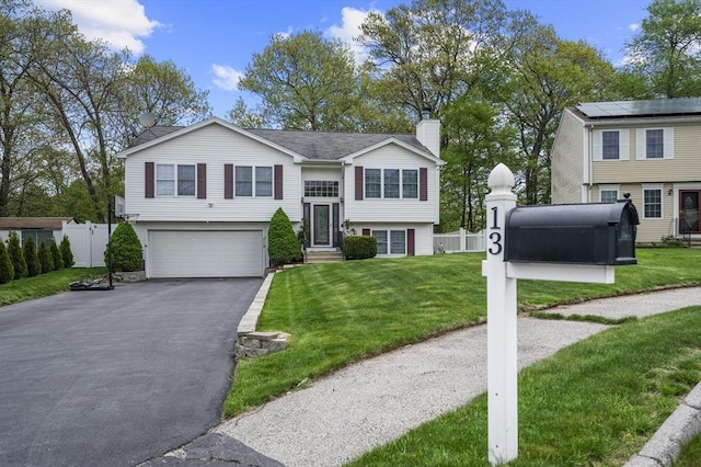 bi-level home with a chimney, asphalt driveway, and an attached garage