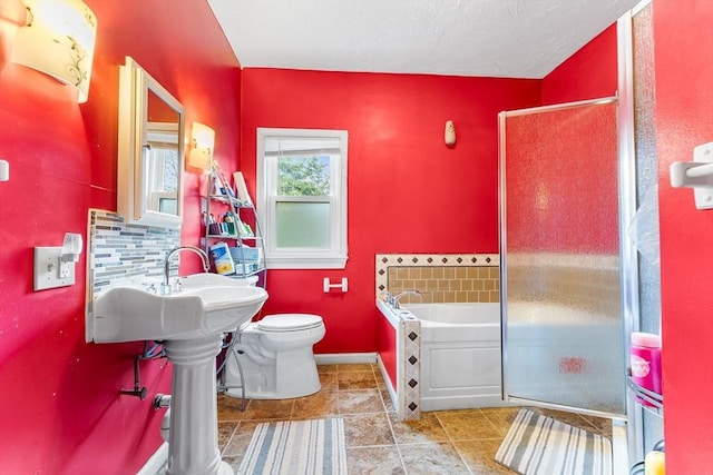 bathroom with toilet, a shower stall, baseboards, and a garden tub