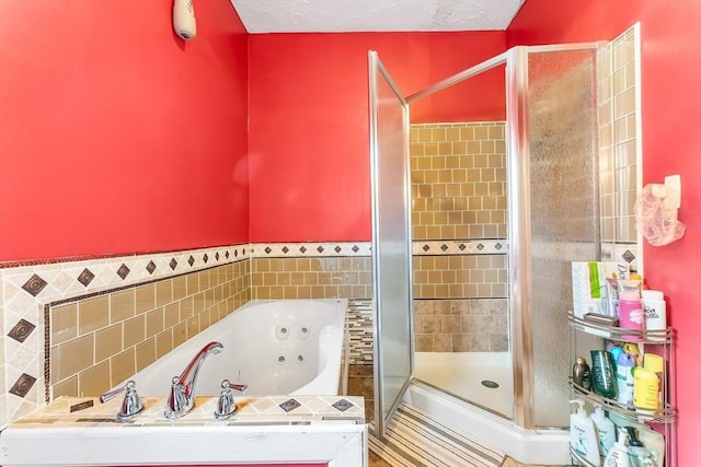 full bath featuring a shower stall, a textured ceiling, and a tub with jets