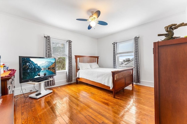 bedroom featuring crown molding, baseboards, ceiling fan, and hardwood / wood-style floors