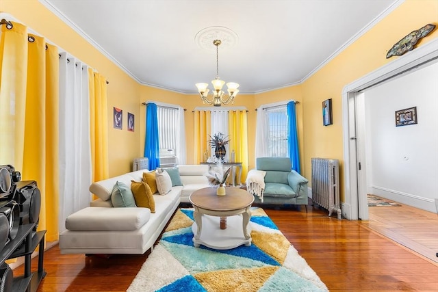 living room featuring crown molding, hardwood / wood-style floors, radiator heating unit, and a notable chandelier