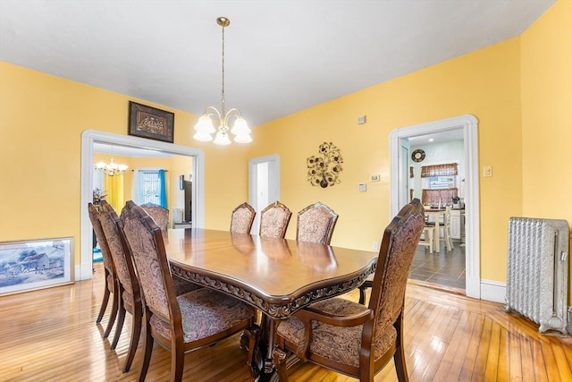 dining area featuring baseboards, light wood-type flooring, and a chandelier