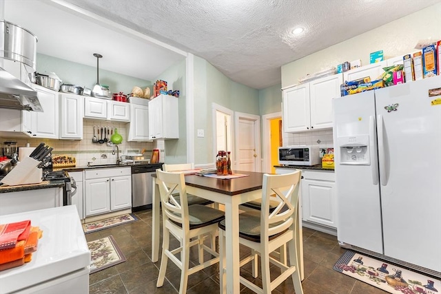 kitchen with white cabinets, dark countertops, backsplash, and appliances with stainless steel finishes