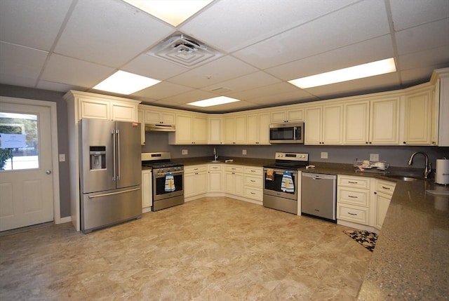 kitchen with sink, cream cabinets, a paneled ceiling, and appliances with stainless steel finishes