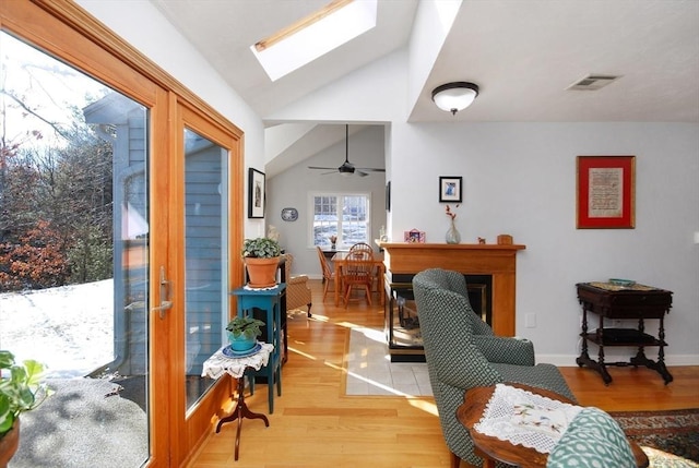 sitting room featuring light hardwood / wood-style floors and vaulted ceiling with skylight