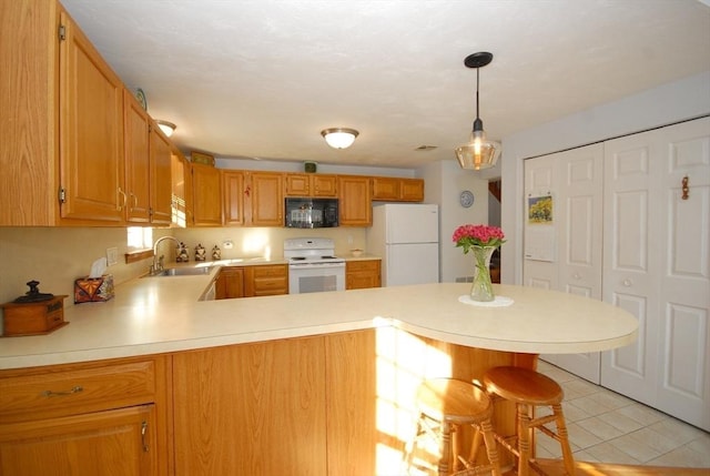 kitchen featuring a kitchen bar, sink, white appliances, and kitchen peninsula