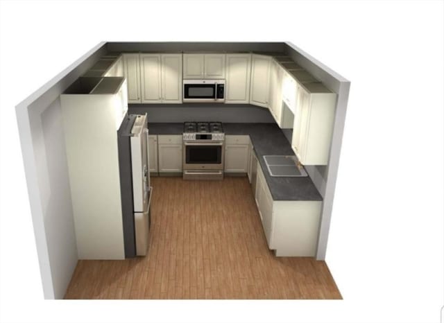 kitchen with stainless steel range with gas cooktop, a sink, fridge, and dark countertops