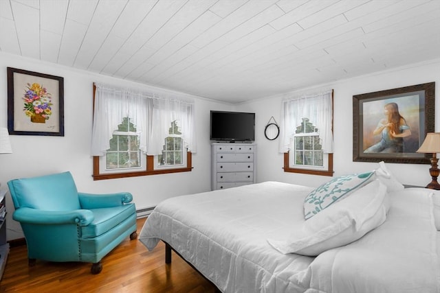 bedroom featuring baseboard heating, wood finished floors, ornamental molding, and wooden ceiling