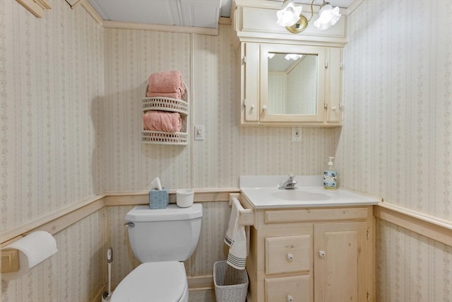 half bathroom with toilet, wainscoting, and vanity