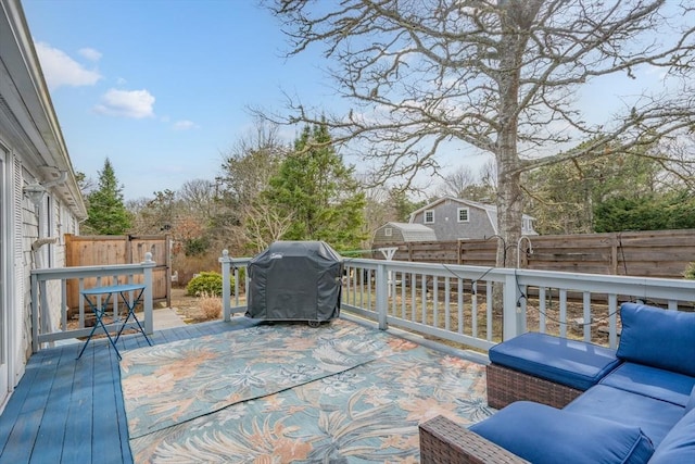 wooden deck with grilling area, a fenced backyard, and an outdoor hangout area