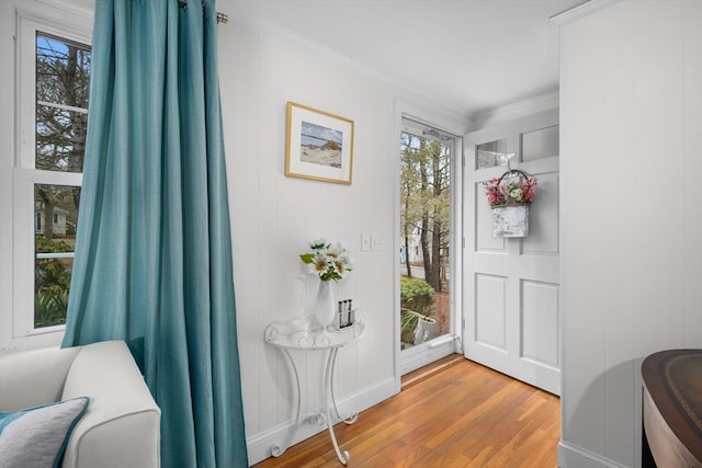 entrance foyer with light wood finished floors, ornamental molding, and a healthy amount of sunlight