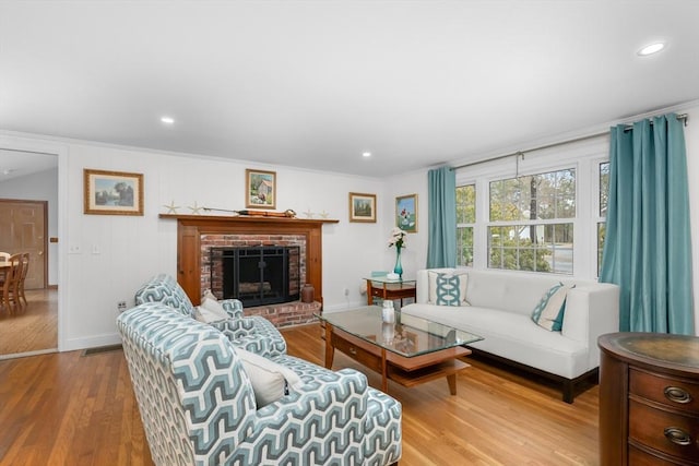 living area featuring ornamental molding, recessed lighting, wood finished floors, and a fireplace