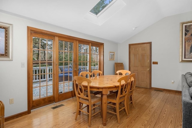 dining area with visible vents, light wood-type flooring, plenty of natural light, and lofted ceiling with skylight