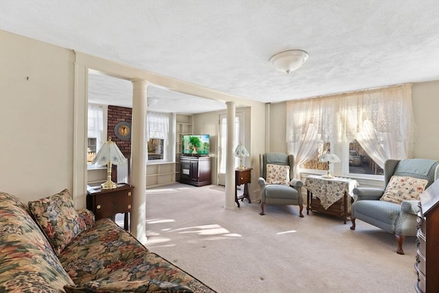 sitting room with plenty of natural light, decorative columns, and carpet flooring