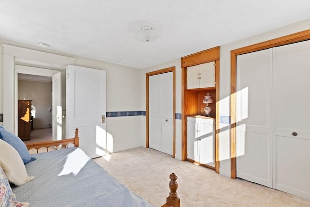 bedroom featuring two closets and light colored carpet