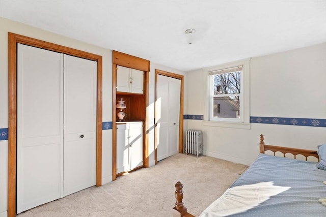 bedroom with multiple closets, radiator, light carpet, and baseboards