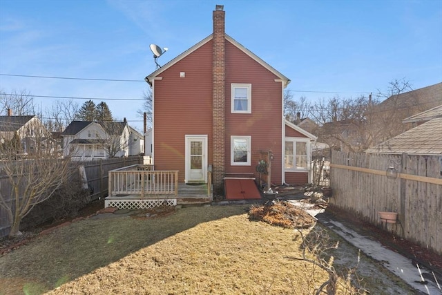 back of house with a deck, a yard, a chimney, and a fenced backyard