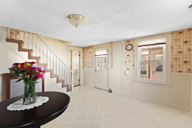 foyer entrance with a wainscoted wall, stairs, baseboards, and tile patterned floors