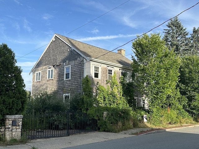 view of side of home featuring a chimney and fence