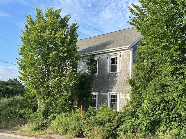 view of side of property with a shingled roof and stucco siding