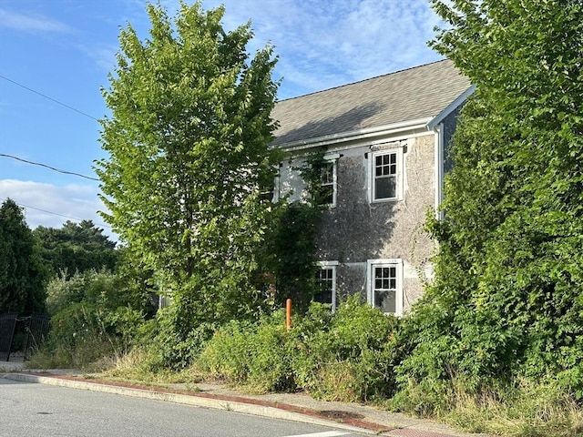 view of side of home featuring roof with shingles and stucco siding