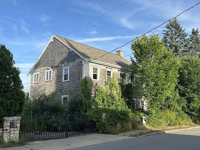 view of property exterior featuring a chimney and fence